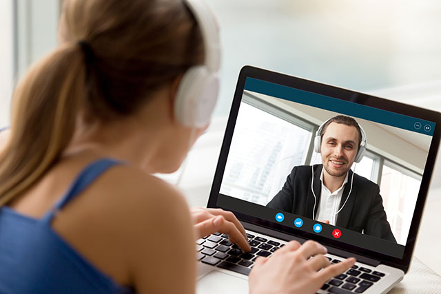 Man and woman in headphones communicating online by video call, looking at full screen videoconferencing app window, webcam videochat, virtual dating, long distance relationships, close up rear view